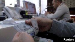 Un changeur d'argent compte des dollars américains pour un client dans le quartier des affaires de Téhéran , en Iran , le 20 janvier 2016 .