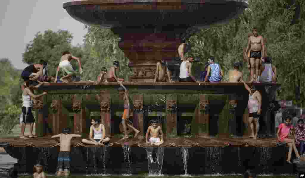 People cool themselves in a fountain near the India Gate monument on a hot day in New Delhi, India.