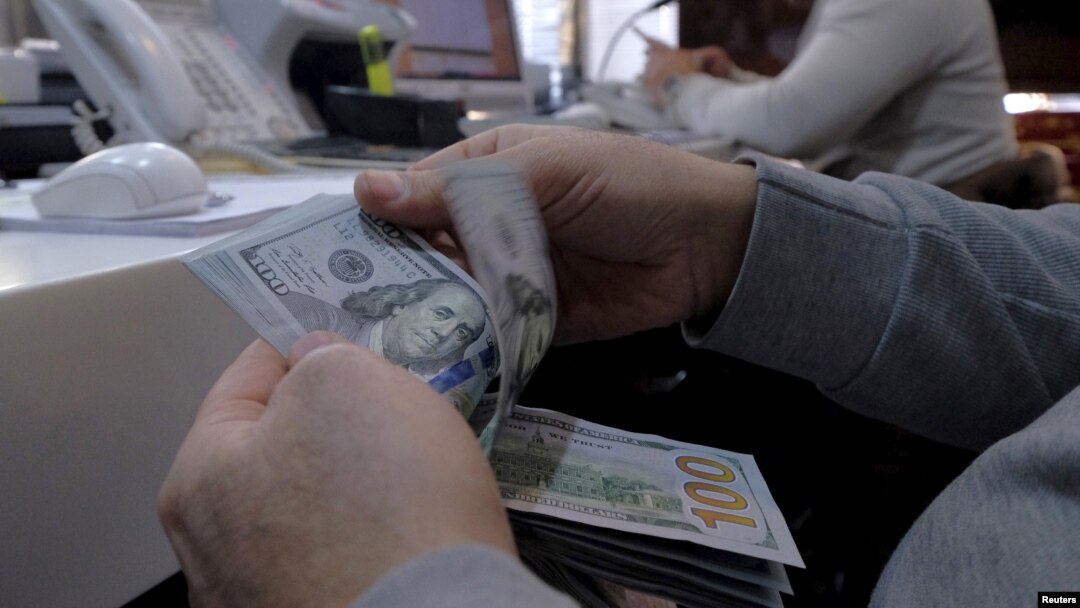 Seorang pegawai tempat pertukaran uang di distrik bisnis di Teheran, Iran, menghitung uang dolar Amerika.