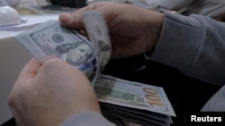 A money changer counts out U.S. dollars for a customer in Tehran's business district, Iran, Jan. 20, 2016. 