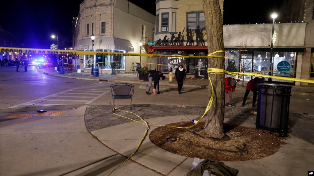 Police walk along the streets in downtown Waukesha, Wis., after a vehicle crashed into a Christmas parade Sunday, Nov. 21, 2021. (AP Photo/Jeffrey Phelps)