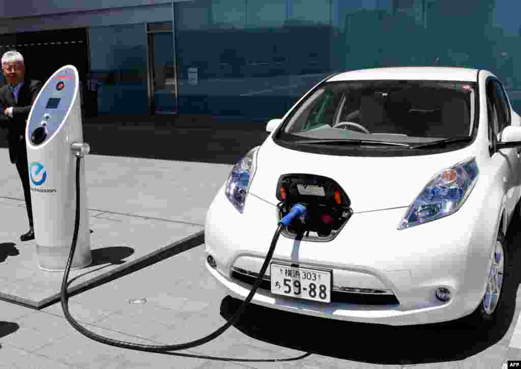 July 11: Nissan Motor Co. chief vehicle engineer Hidetoshi Kadota demonstrates a quick charge of a Nissan Leaf by a solar-assisted EV charging system at Nissan's global headquarters in Yokohama, Japan. (AP Photo/Koji Sasahara)