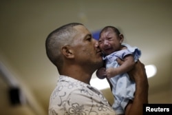 FILE - Geovane Silva holds his son Gustavo Henrique, who has microcephaly, at the Oswaldo Cruz Hospital in Recife, Brazil, Jan. 26, 2016.