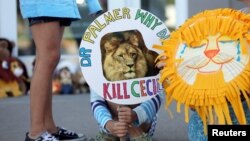 FILE: Piper Hoppe, 10, from Minnetonka, Minnesota, holds a sign at the doorway of River Bluff Dental clinic in protest against the killing of a famous lion in Zimbabwe, in Bloomington, Minnesota July 29, 2015. 