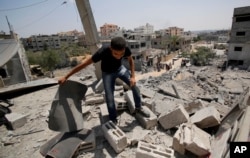 A member of the Abed Aal family salvages belongings from his family's house destroyed in an overnight Israeli strike in Gaza City, Aug. 2, 2014.