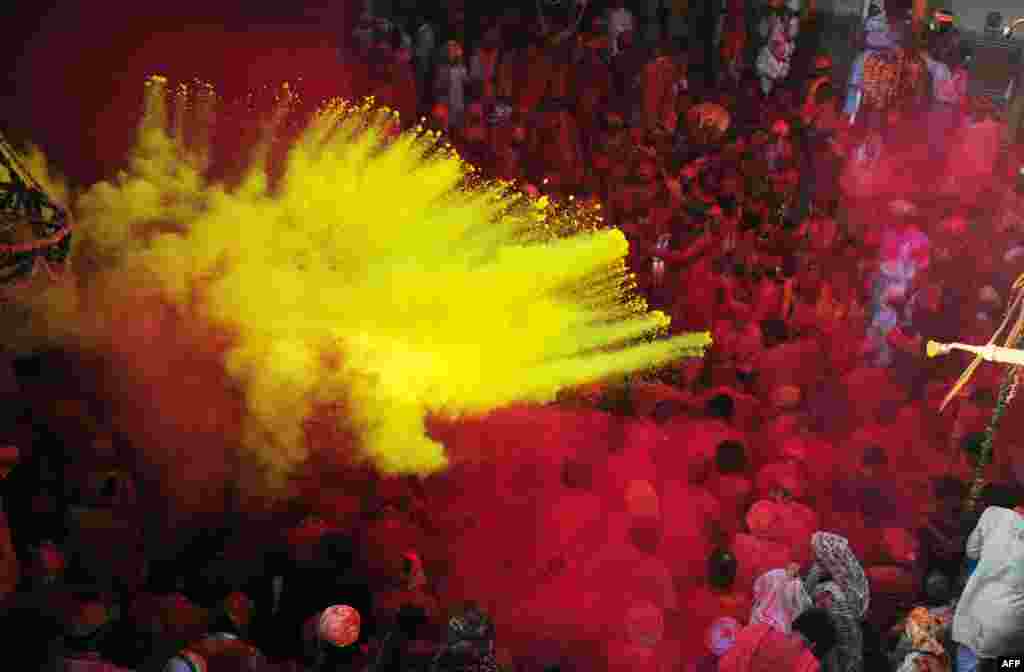 Indian Hindu devotees throw coloured powder at the Radha Rani temple during the Lathmar Holi festival in Barsana.
