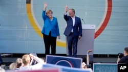 Chancellor Angela Merkel and Armin Laschet, top candidate for the upcoming election, wave to supporters at the final election campaign event of the Christian Democratic Party, CDU, ahead of the German general election, in Aachen, Germany, Sept. 25, 2021. 