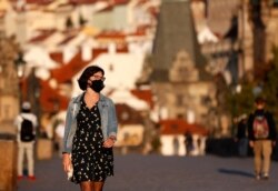 A young woman wearing a face mask walks across the medieval Charles Bridge in Prague, Czech Republic, Sept. 18, 2020.