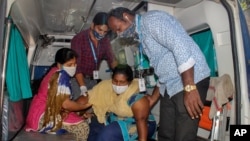 A patient is assisted to get down from an ambulance at the district government hospital in Eluru, Andhra Pradesh state, India, Dec.8, 2020, where health officials and experts are baffled by a mysterious illness that has left over 500 people hospitalized.