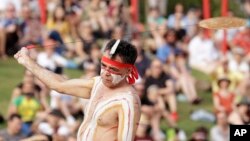 An Aboriginal man swings an instrument known as a Bullroarer during the Wugulora Indigenous Morning Ceremony as part of Australia Day celebrations in Sydney, Australia, Sunday, Jan. 26, 2020. (AP Photo/Rick Rycroft)