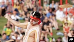 Seorang pria Aborigin mengayunkan alat musik tradisional Bullroarer saat berlangsungnya Upacara Pagi Adat Wugulora, dalam perayaan Hari Australia di Sydney, Australia, Minggu, 26 Januari 2020. (Foto AP / Rick Rycroft)