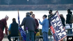 FILE - A flag promotes former President Donald Trump and John F. Kennedy Jr., killed in a plane crash in 1999, as potential running mates in presidential elections, March 13, 2021, at rally in Olympia, Wash. The flag references postings by "Q," purportedly a government insider.