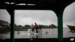 ARCHIVO - Un hombre anda en bicicleta bajo la lluvia provocada por la tormenta tropical Bonnie en Bluefields, Nicaragua, el viernes 1 de julio de 2022.