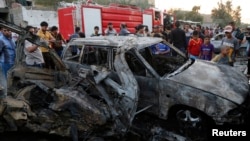 People gather at the site of a car bomb attack in Sadr City district of Baghdad, Iraq, May 15, 2014.