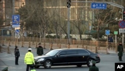 Petugas keamanan bersiaga penuh saat limusin Mercedes dalam iring-iringan yang diyakini membawa pemimpin Korea Utara Kim Jong-un melewati jalan di Beijing, Rabu, Januari 9, 2019.
