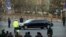 Security officials stand guard while a Mercedes limousine in a motorcade believed to be carrying North Korean leader Kim Jong Un passes along a street in Beijing, Wednesday, Jan. 9, 2019. 
