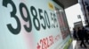 People walk in front of an electronic stock board showing Japan's Nikkei index at a securities firm in Tokyo, Dec. 27, 2024.