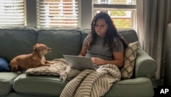 In this March 27, 2020 photo, Vicktery Zimmerman works from her home in Chicago during the order to shelter in place. A self-proclaimed extrovert, Zimmerman has come up with workarounds like video calls to deal with social distancing. (Justin Zimmerman via AP)