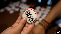 FILE - An Egyptian buys a pin with the Boycott, Divestment and Sanctions (BDS) logo during the launch of the Egyptian campaign that urges boycott, divestment and sanctions against Israel. The BDS campaign is behind the proposed boycott of Israeli universi