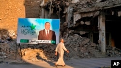 FILE - A campaign poster for parliamentary elections is displayed near destroyed buildings from fighting between Iraqi forces and the Islamic State group in Mosul, Iraq, Oct. 3, 2021.