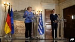 German Chancellor Angela Merkel speaks next to Greek Prime Minister Kyriakos Mitsotakis during a join news conference after their meeting at Maximos Mansion in Athens, Greece, Oct. 29, 2021.