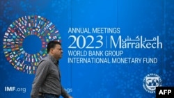 FILE - A pedestrian walks past a billboard announcing the World Bank Group and International Monetary Fund annual meetings, on the side of the International Monetary Fund headquarters in Washington, DC, on October 5, 2023.