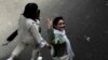 FILE - An Iranian woman without a mandatory headscarf, or hijab, flashes a victory sign as she walks at the old main bazaar of Tehran, Iran, June 13, 2024. 