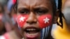 Seorang mahasiswa Papua dengan wajah dicat bendera "Bintang Kejora" meneriakkan slogan-slogan dalam unjuk rasa di depan Istana Kepresidenan di Jakarta, 28 Agustus 2019. 
