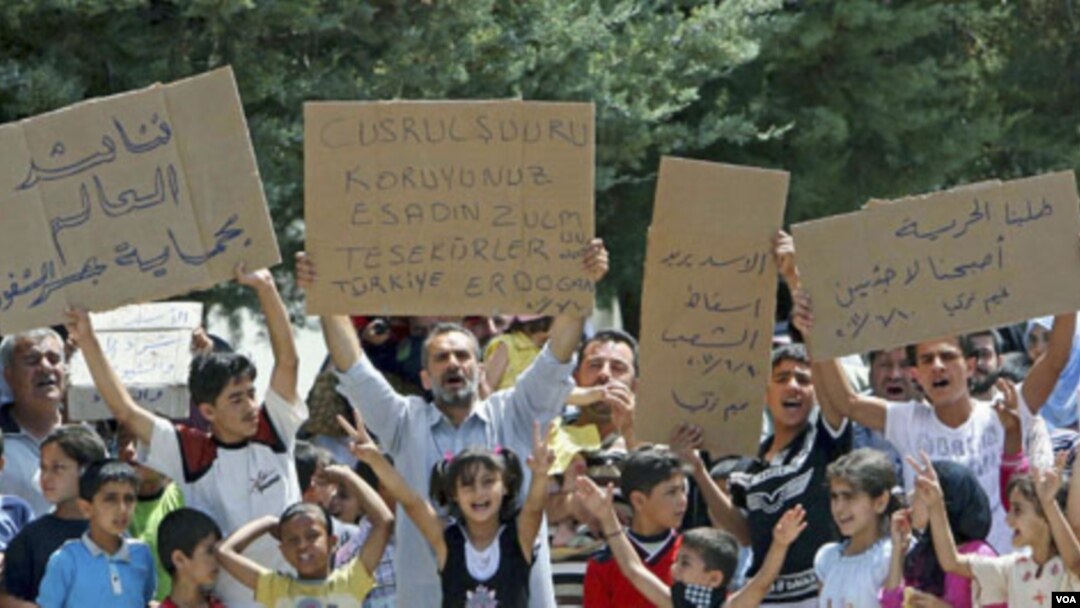 Para pengungsi Suriah di Turki melakukan unjuk rasa dengan membawa poster 'Lindungi Jisr al-Shughour dari Bashar al-Assad' (10/6).