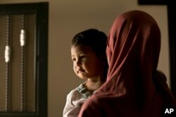 In this March 26, 2019, photo, Aliya, a 24 year-old Indonesian national, poses for a portrait with her son, Yahya, at Camp Roj in north Syria. (AP Photo/Maya Alleruzzo)