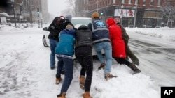 People push a stranded taxi during a snowstorm, Tuesday, March 13, 2018, in Boston. The third major nor’easter in two weeks slammed New England on Tuesday, bringing blizzard conditions and more than a foot of snow to some communities.