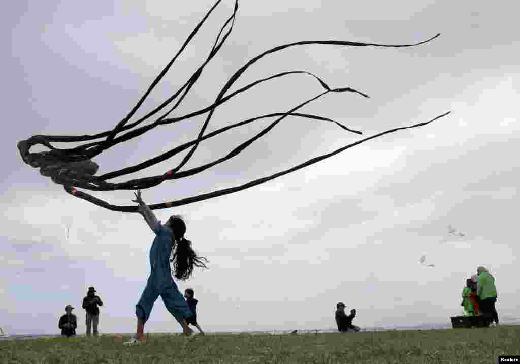 A girl plays with a kite at the 30th Cape Town International Kite Festival in Cape Town, South Africa. Kite enthusiasts gather to fly colorful kites to raise awareness for mental health.