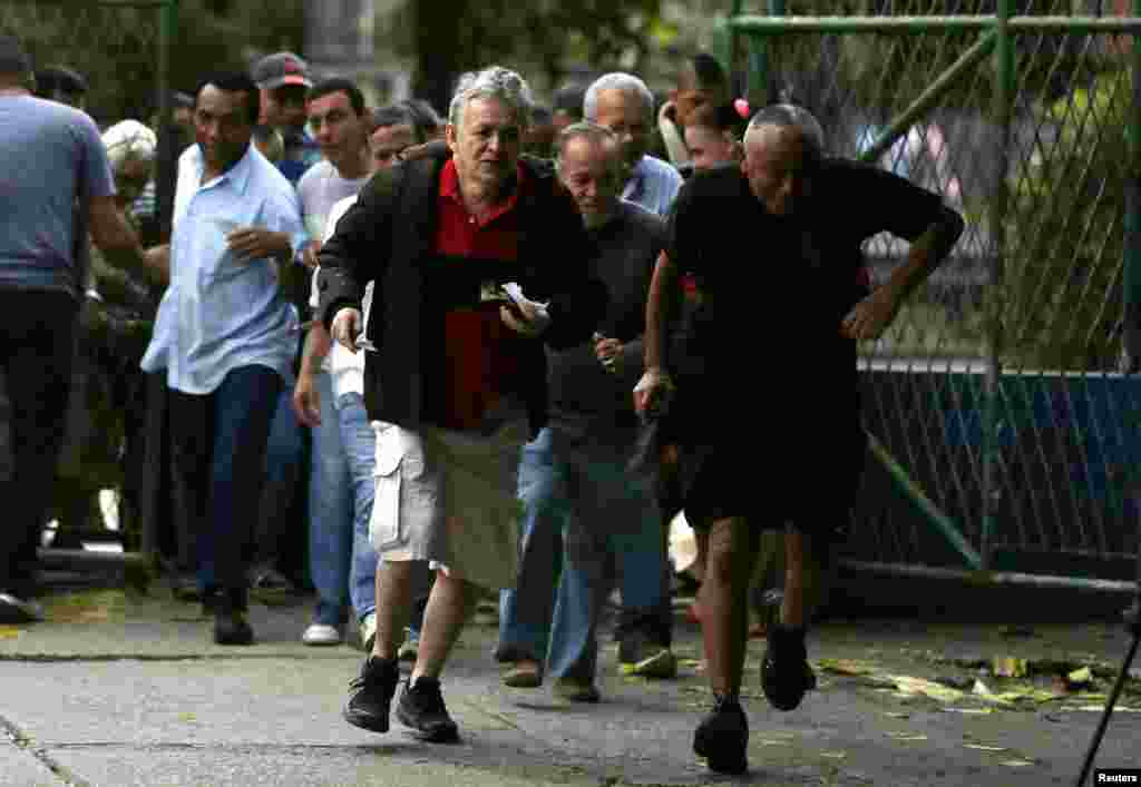 Residents run into a school to vote at the Rocinha slum in Rio de Janeiro, Oct. 5, 2014.