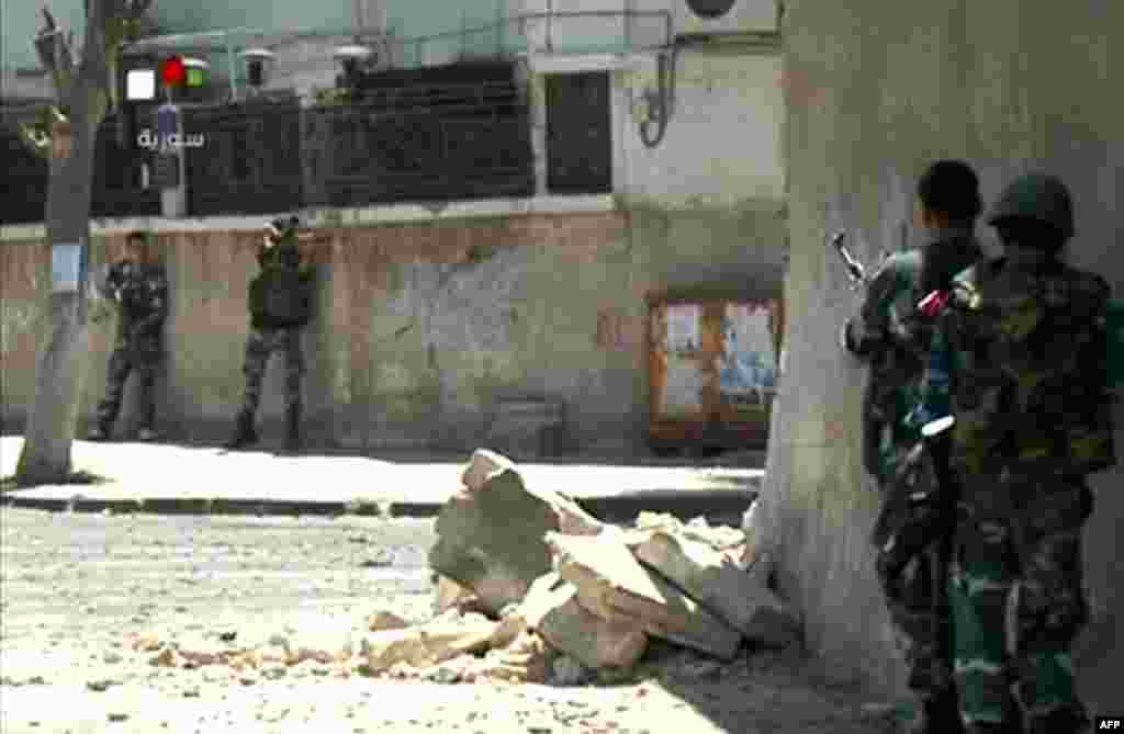 An image taken from Syrian television shows Syrian security forces taking position during armed clashes with gunmen in the Al-Midan district of Damascus, July 18, 2012.