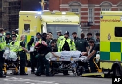 Emergency services transport an injured person to an ambulance, close to the Houses of Parliament in London, March 22, 2017.