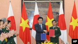 Menteri Pertahanan Jepang Minoru Kihara (kedua dari kanan) dan Menteri Pertahanan Vietnam Phan Van Giang (kanan), bertukar dokumen yang ditandatangani di Hanoi, Vietnam, Selasa, 6 Agustus 2024. (Nguyen Trong Duc/VNA via AP)