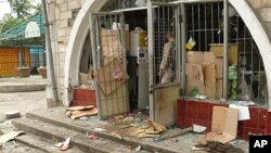 A man looks at a vandalized Kyrgyz building in the streets of Osh, 11 Jun 2010