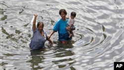 Bangkok residents wade through deep floodwaters in Bangkok, Thailand, Sunday, Oct. 30, 2011. Thailand's prime minister is expressing optimism that Thailand's worst flooding in a half-century will mostly spare Bangkok. (AP Photo/Sakchai Lalit)