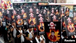 FILE - Activists displaying portraits of people who killed themselves via self-immolation take part in a rally to support Tibet in Taipei, March 10, 2013. 