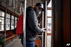A man wearing a protective mask steps off an empty tram in downtown Milan, Italy, Feb. 26, 2020.