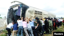Warga berusaha mengembalikan posisi sebuah bis yang terbalik. Bis tersebut membawa siswa sekolah dasar di propinsi Hainan 10 April 2014. (Foto: dok.)