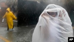 Una mujer cubre con una bolsa plástica de la lluvia al acerarse el huracán María a República Dominicana.