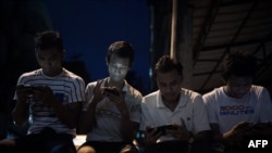 Young men browse their Facebook wall on their smartphones as they sit in a street in Yangon on August 20, 2015. Facebook remains the dominant social network for US Internet users, while Twitter has failed to keep apace with rivals like Instagram and Pinterest, a study showed. AFP