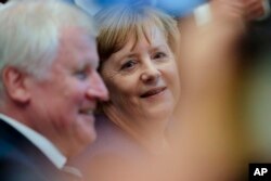 Angela Merkel, center, German Chancellor and Christian Democratic Union, CDU, party chairwoman and Bavarian state governor and Christian Social Union, CSU, party chairman Horst Seehofer, left, attend the parliamentary caucus of Merkel's conservative Union bloc in Berlin, Germany, Sept. 26, 2017.