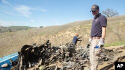 In this image taken Jan. 27, 2020, and provided by the National Transportation Safety Board, NTSB investigators Adam Huray, right, and Carol Hogan examine wreckage as part of the investigation of a helicopter crash near Calabasas, California.