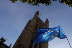 FILE - The sun shines through a European Union flag hanging outside Parliament in London, Oct. 28, 2019.