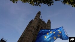 FILE - The sun shines through a European Union flag hanging outside Parliament in London, Oct. 28, 2019. 