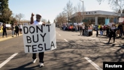 People protest against Tesla and Elon Musk outside of a Tesla dealership in Palo Alto, California, on March 8, 2025. U.S. President Donald Trump said on March 11 he would buy a Tesla vehicle as a show of support as the company becomes a focal point of protests against Musk.