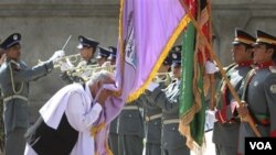 Ashraf Ghani, kepala Komisi Peralihan keamanan, mencium bendera polisi Afghanistan saat penyerahan keamanan di Bazarak, provinsi Panjshir (24/7).