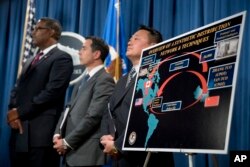 Law enforcement officials appear before a drug distribution poster during a news conference at the Justice Department in Washington, Oct. 17, 2017, to announce the indictments of two Chinese fentanyl trackers.